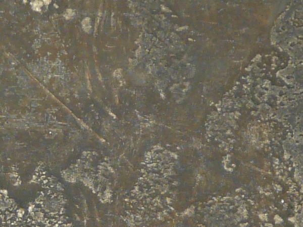 Uneven roofing material in dark shades of grey and brown with scratches and spots.