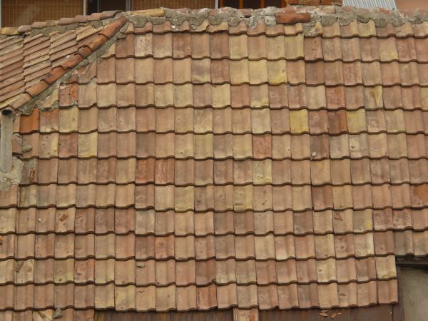 Slightly worn roofing texture of even, brown shingles with spots.