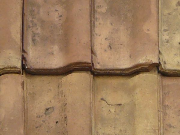Slightly worn roofing texture of even, brown shingles with spots.