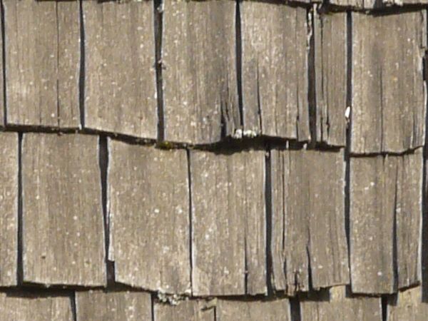 Roof texture of splintering, wooden planks in grey color.