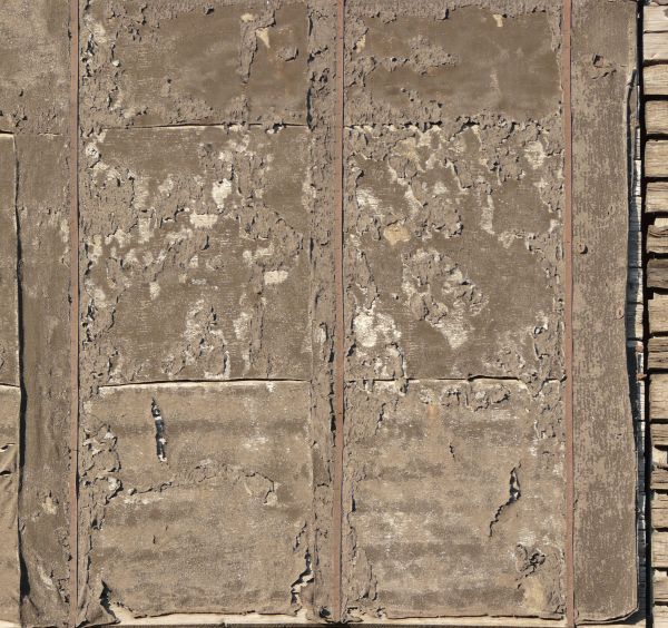 Texture of very worn roofing material nailed down with metal straps.