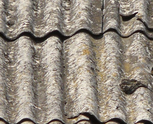 Roof texture of curved, grey metal slate. Slate surface is very worn.