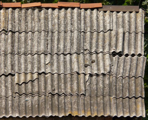 Roof texture of curved, grey metal slate. Slate surface is very worn.