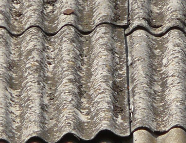 Roof texture of curved, grey metal slate. Slate surface is very worn.