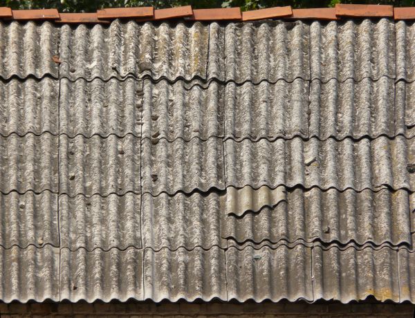 Roof texture of curved, grey metal slate. Slate surface is very worn.