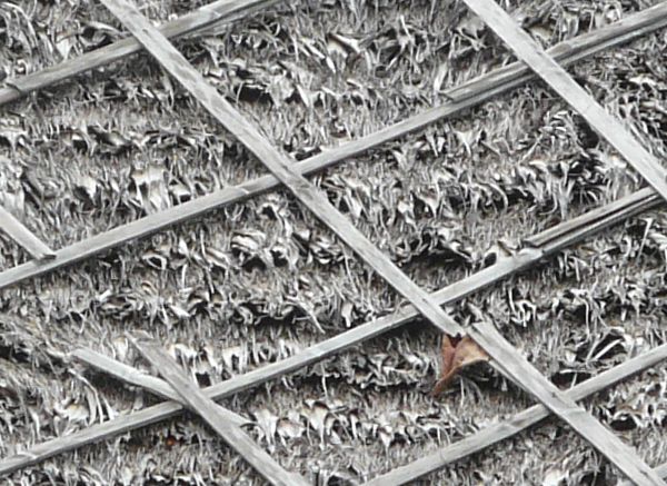 Roof texture consisting of dry grey grass with wooden planks in diamond pattern.