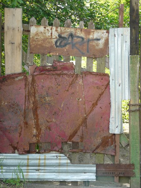 Fence texture, made up of various pieces of wood, metal and rusted panels.