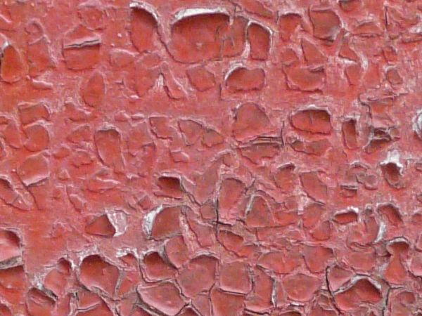 Chipping red paint texture, with an area of heavy rust visible underneath, and several white stains.