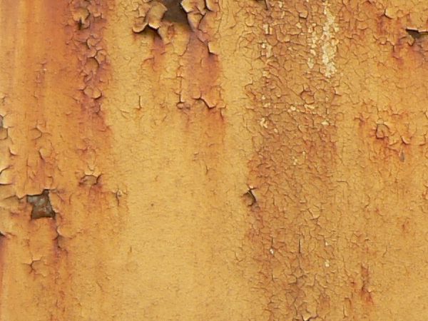 Red and white metal texture, with large chipping areas and completely covered by orange and brown rust stains.