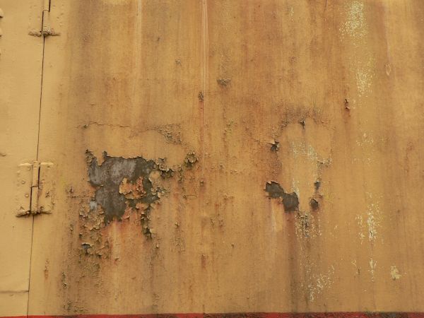 Red and white metal texture, with large chipping areas and completely covered by orange and brown rust stains.