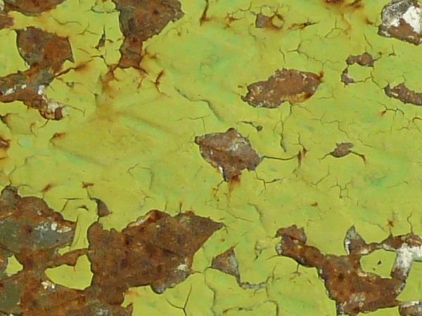 Rusted metal texture, covered by a chipping surface of lime green paint with extensive white staining.