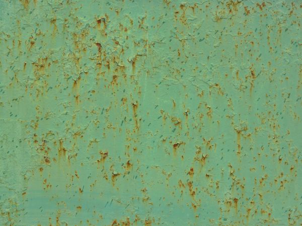 Light green metal texture, with small cracks and brown rust stains visible throughout.