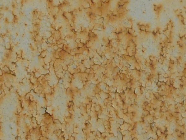 White metal texture covered with many faint cracks, rust patches and large areas of light brown staining.