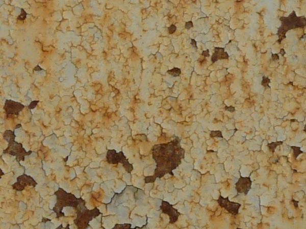 White metal texture covered with many faint cracks, rust patches and large areas of light brown staining.