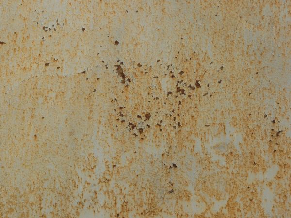 White metal texture covered with many faint cracks, rust patches and large areas of light brown staining.