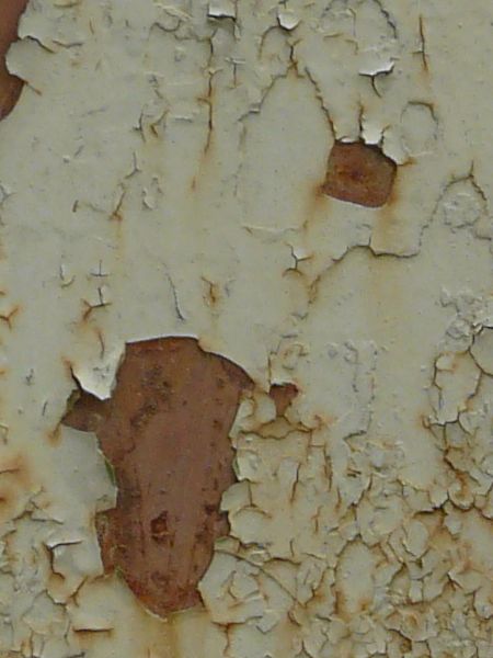 White paint texture, peeling off of a rusted metal surface. Brown rust stains are also visible on the paint.