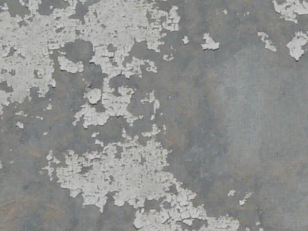 White painted metal texture, chipping off of a grey surface with faint brown rust stains.