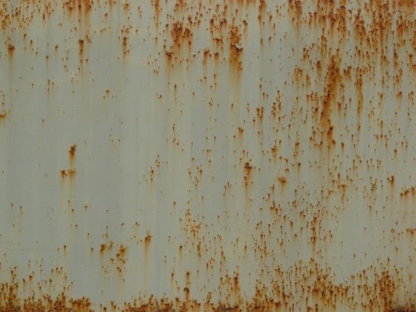 Orange rust marks texture, scattered over a surface of white metal. Large stains and completely rusted patches are also visible.