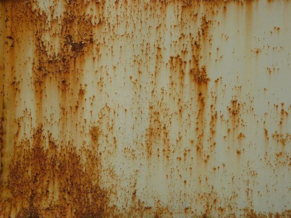 Orange rust scratches texture, spread irregularly in small marks and patches on a stained surface of white metal.