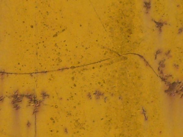 Yellow metal texture with various thin rust scratches and large rust stains visible througout.