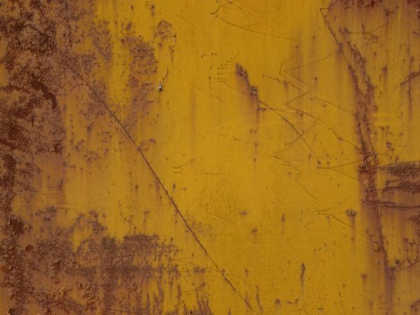 Yellow metal texture with various thin rust scratches and large rust stains visible througout.