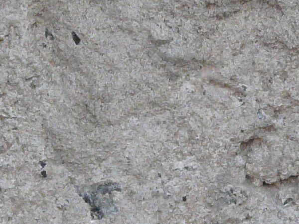 Grey ground texture in various degrees of releif, with rough edges and some spots of dark soil.