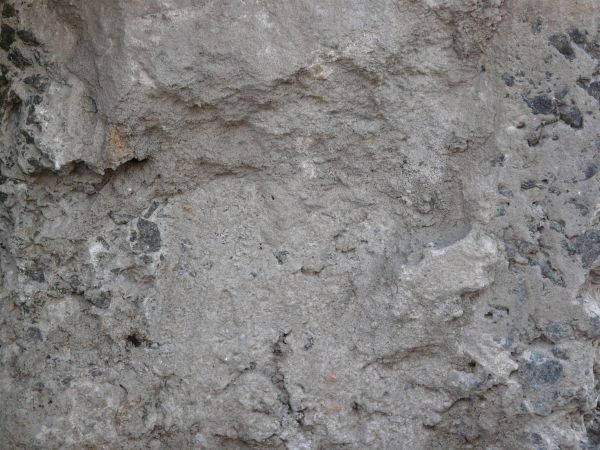 Grey ground texture in various degrees of releif, with rough edges and some spots of dark soil.