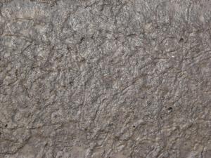 Rocky brown mud texture, with a shiny, bumpy surface full of small holes and indentations.