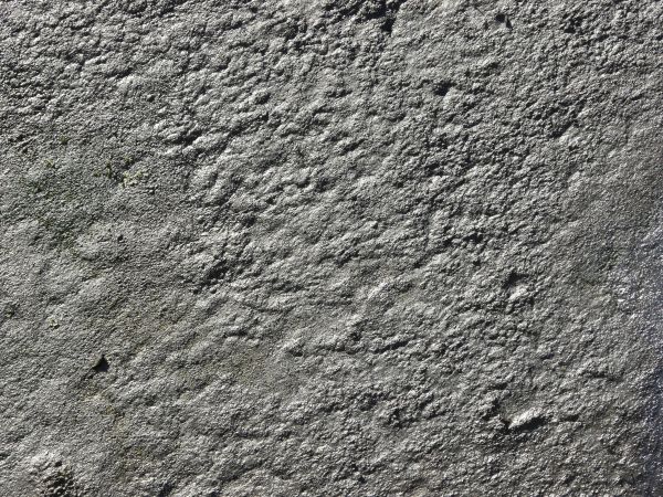 Hardened grey mud texture, dried into a smooth, porous and uneven surface.