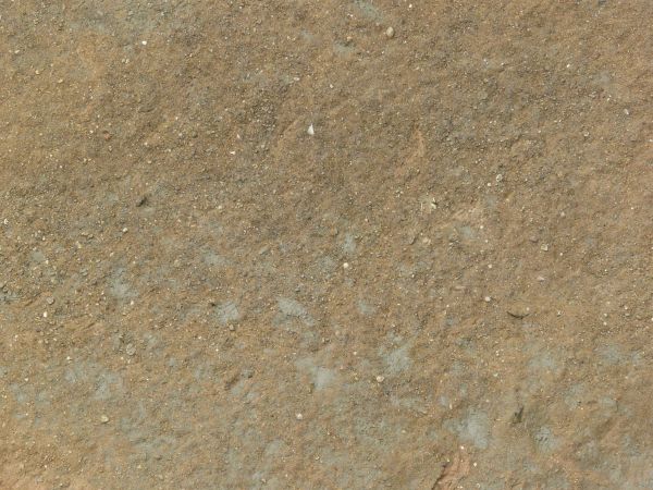 White mud texture with a layer of fine, reddish brown rock spread unevenly over the surface.