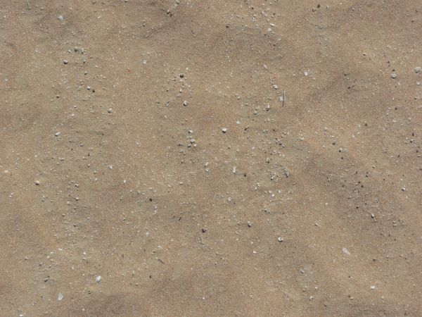 Tan sand texture, with small rocks visible upon and within the surface.
