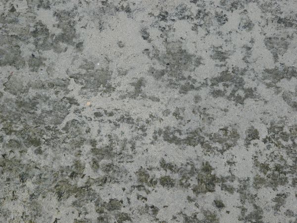 Rocky grey soil texture, covered irregularly by a thin layer of white sand.