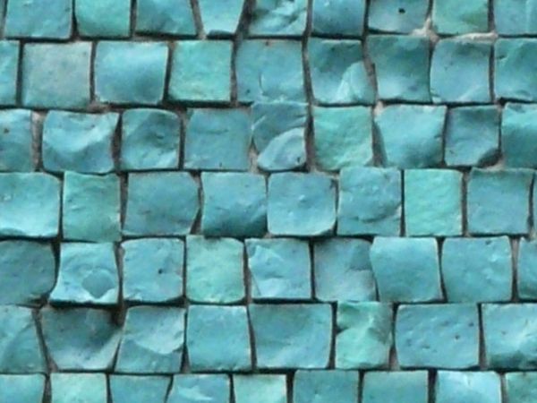 Small, square tiles in shiny, turquoise tones with extremely rough and irregular surfaces.