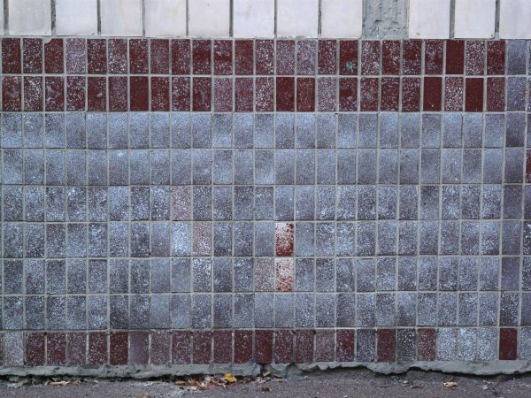 Rectangular tiles in red and grey tones set in even formation with dirty, spotted surface.