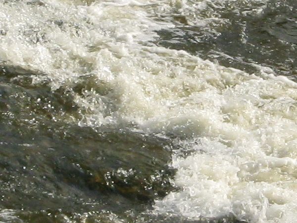 River water texture with very rough, foamy surface and dark, murky consistency throughout.
