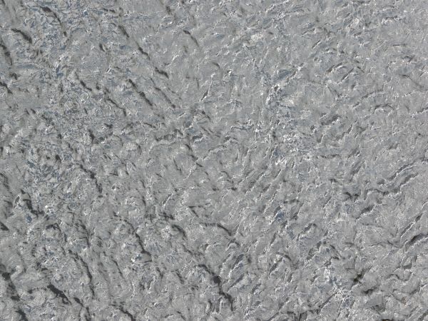 Water texture with small waves and very shiny, grey surface.