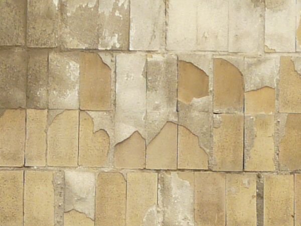 Glass brick windows texture, with several holes and broken areas, and large clouded panes set over the bricks. The windows are set in a wall of stained yellow brick.