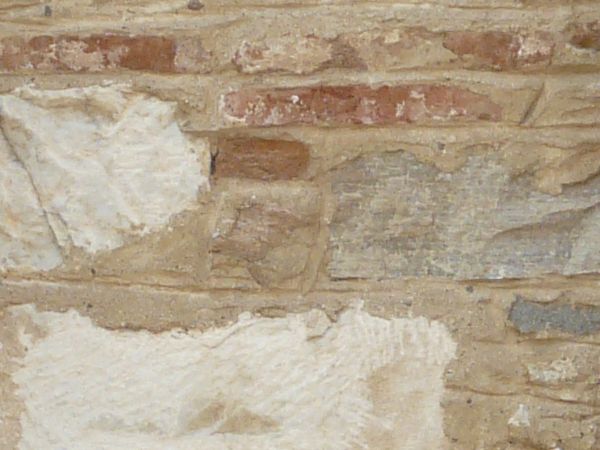 Brown windows texture, covered with elaborately designed iron bars, and set in walls of multicolored brick that have been partially cemented over.