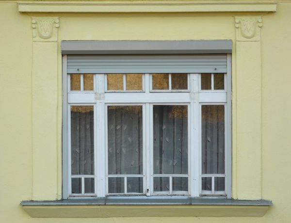 Tall windows texture with white wood trim, set in a yellow stone wall. Thin curtains with a leaf pattern are visible behind the windows.