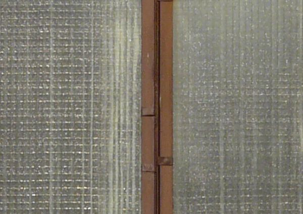 Clouded windows texture, with brown wood separating the tall panes. Crossed boards are visible behind the windows.