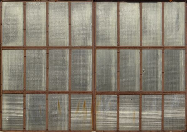 Clouded windows texture, with brown wood separating the tall panes. Crossed boards are visible behind the windows.
