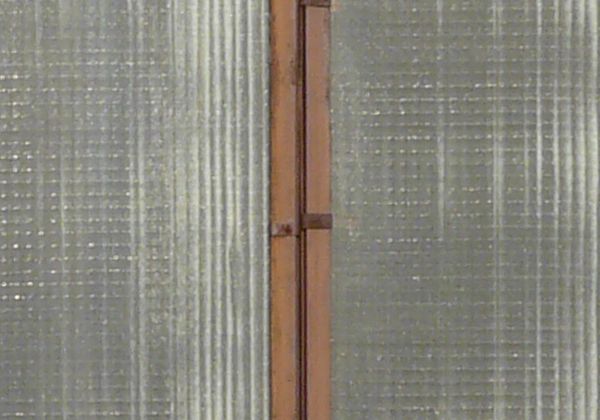 Clouded windows texture, with brown wood separating the tall panes. Crossed boards are visible behind the windows.