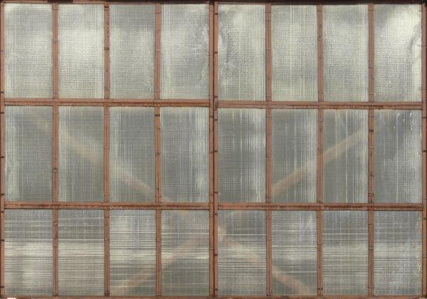 Clouded windows texture, with brown wood separating the tall panes. Crossed boards are visible behind the windows.
