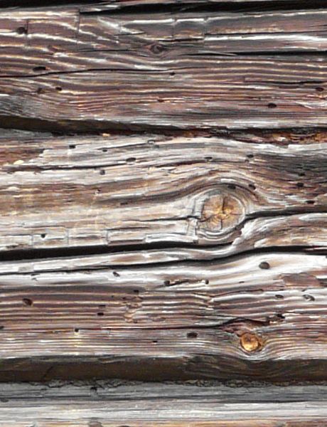 Texture of cabin made of wood logs set in horizontal fashion with very rough, worn surface.