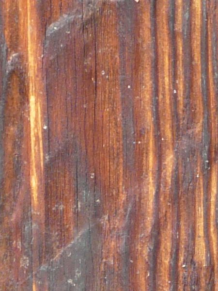 Old wood texture, with grain in various hues of brown, and a layer of white dust covering the surface.