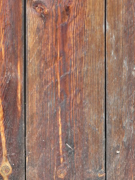 Old wood texture, with grain in various hues of brown, and a layer of white dust covering the surface.