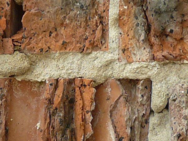 Texture of old, brick wall in red and black tones with very rough surface.