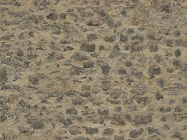 Medieval stone wall of grey stones of various shapes in thick, beige concrete.