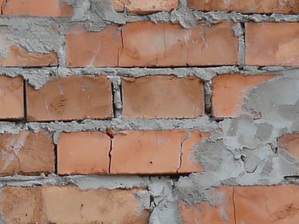 Red brick wall with rough grey cement job.