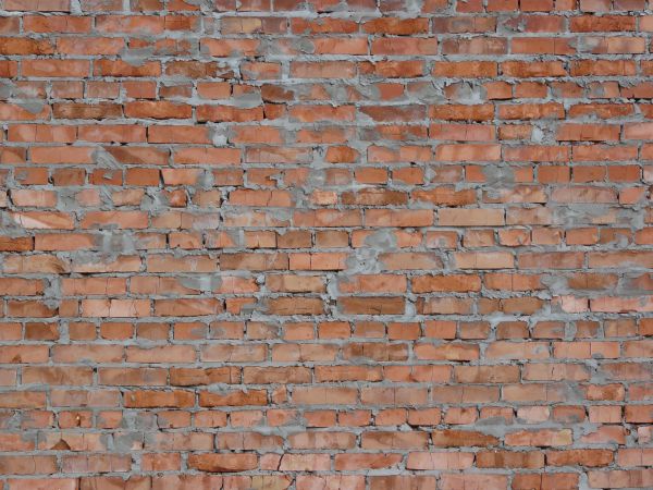 Red brick wall with rough grey cement job.